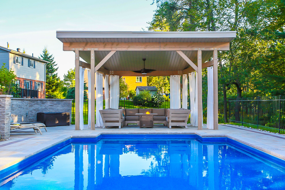 This is an example of a large modern back patio in Toronto with a gazebo and concrete paving.