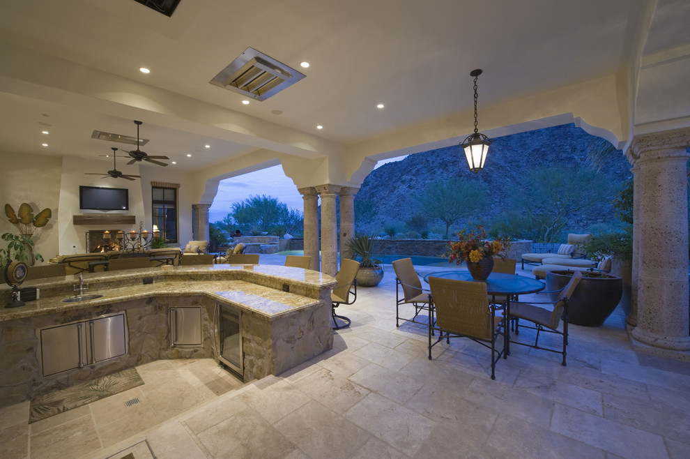 Patio kitchen - large contemporary backyard stone patio kitchen idea in Orange County with a roof extension