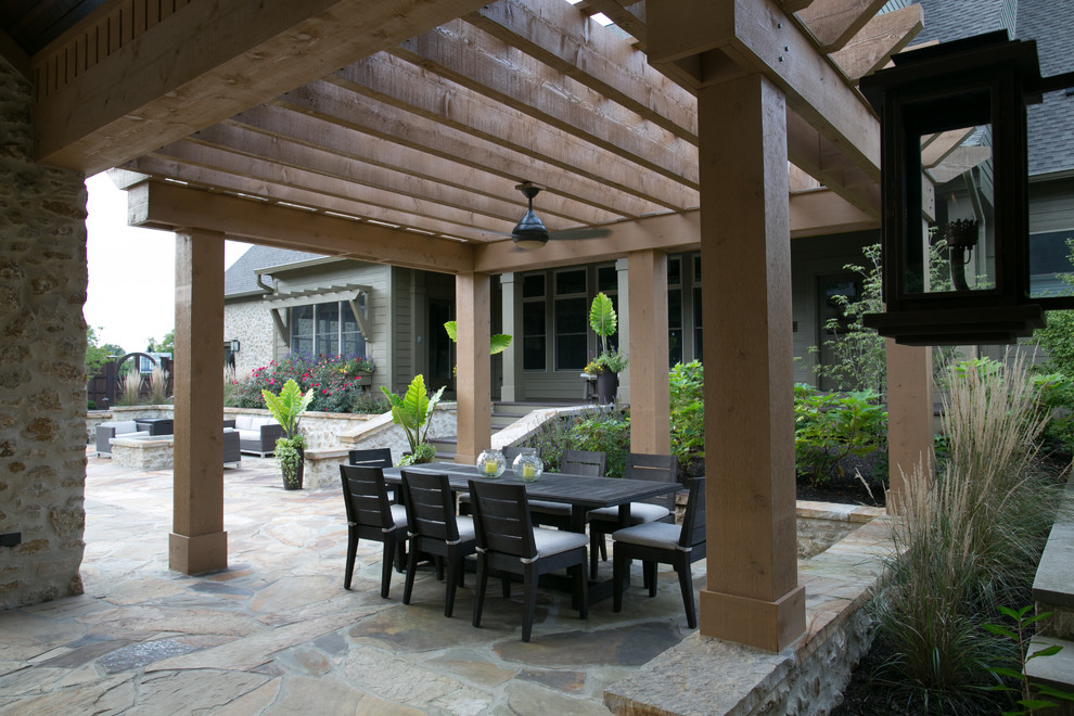 Foto di un grande patio o portico classico dietro casa con pavimentazioni in pietra naturale e una pergola