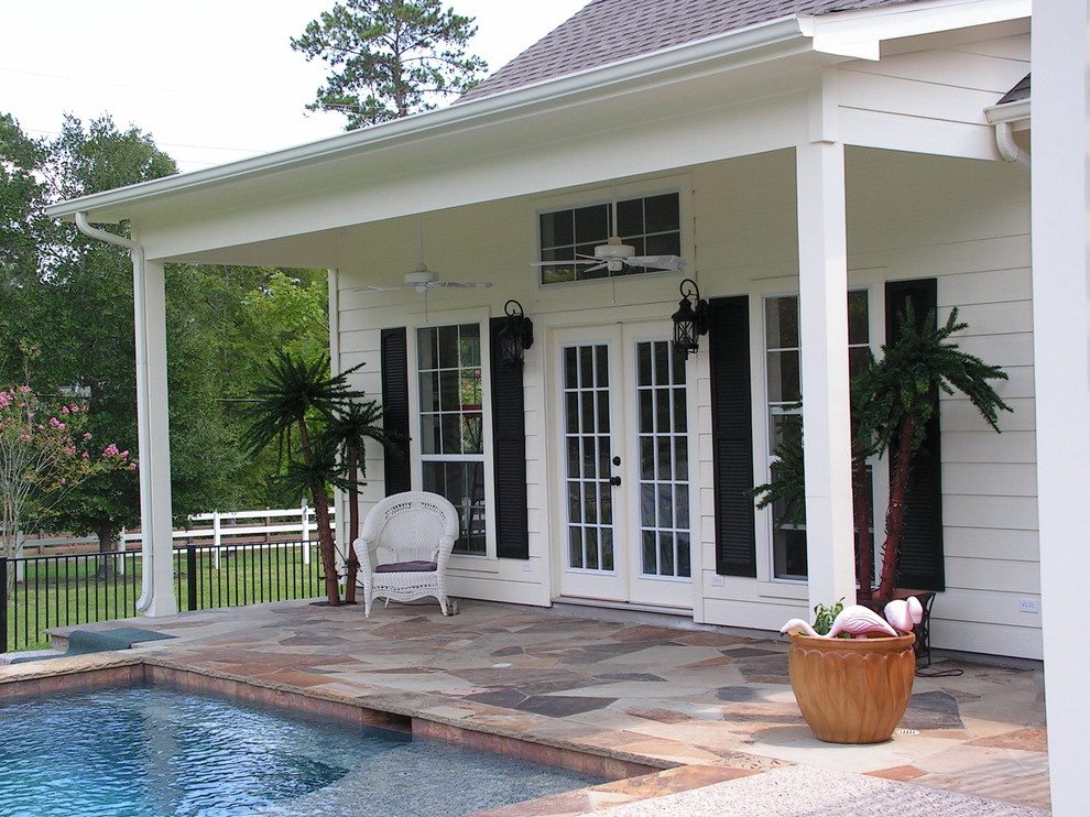 Inspiration for a large classic back patio in Houston with a water feature, natural stone paving and a roof extension.