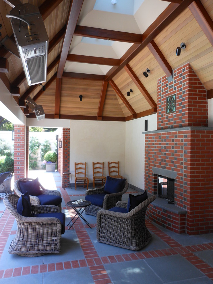 Esempio di un patio o portico tradizionale di medie dimensioni e dietro casa con un focolare, pavimentazioni in cemento e un tetto a sbalzo