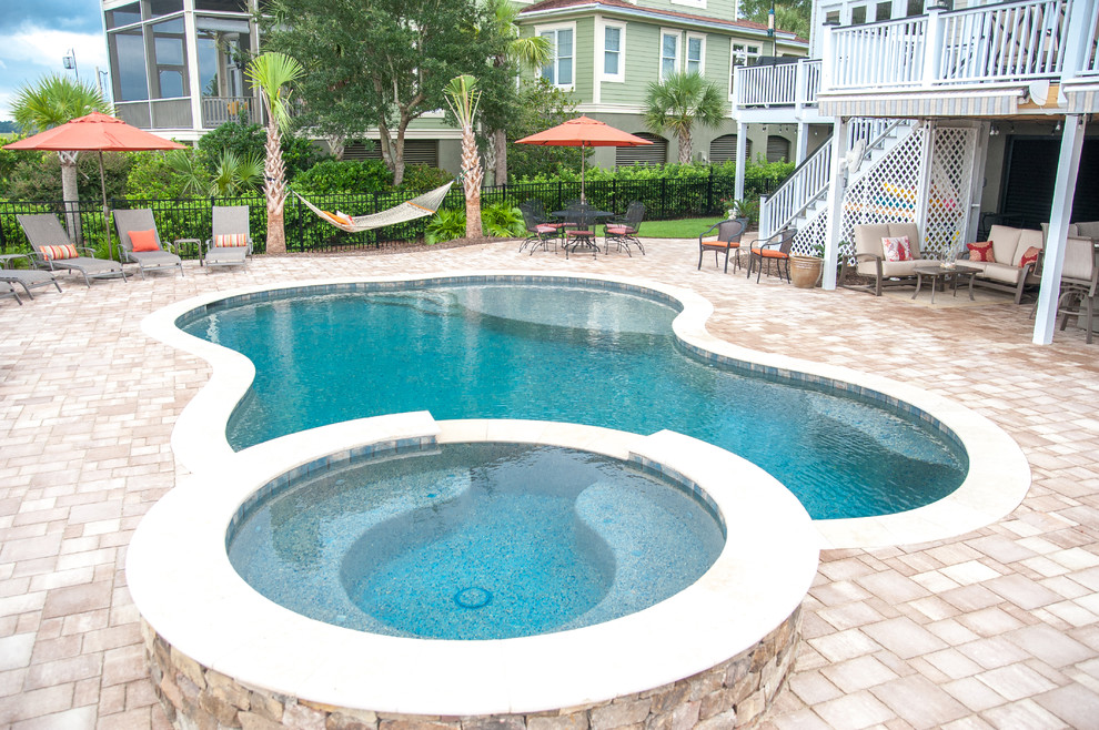 На фото: большой бассейн на заднем дворе в морском стиле с покрытием из каменной брусчатки с