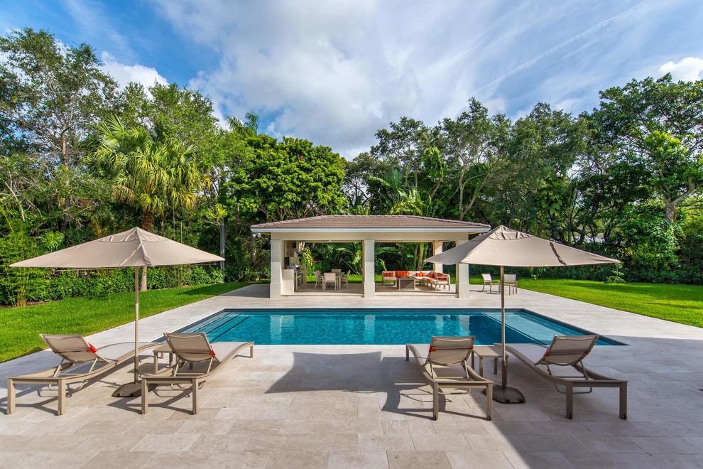 This is an example of a large contemporary back patio in Miami with natural stone paving, a gazebo and an outdoor kitchen.