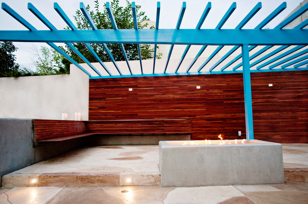 Idée de décoration pour une terrasse latérale design avec un foyer extérieur et du béton estampé.