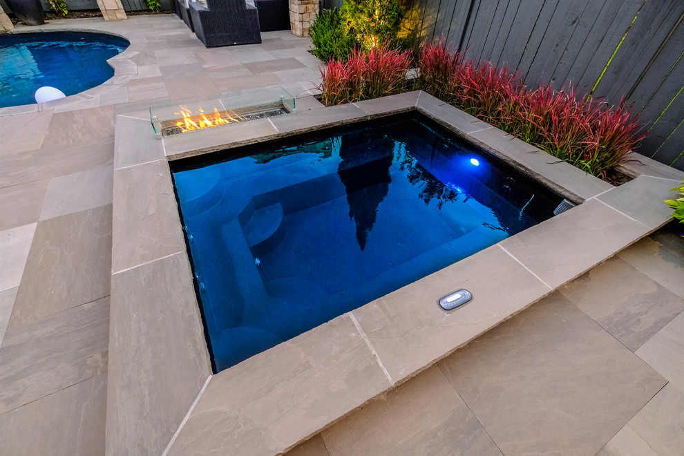 This is an example of a small classic back swimming pool in Toronto with natural stone paving.
