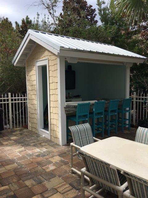 Idee per un piccolo patio o portico tropicale dietro casa con pavimentazioni in mattoni e un gazebo o capanno