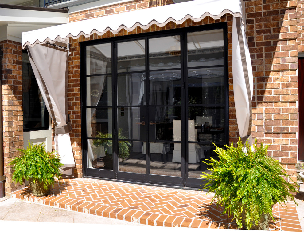 This is an example of a medium sized traditional back patio in Atlanta with brick paving and an awning.