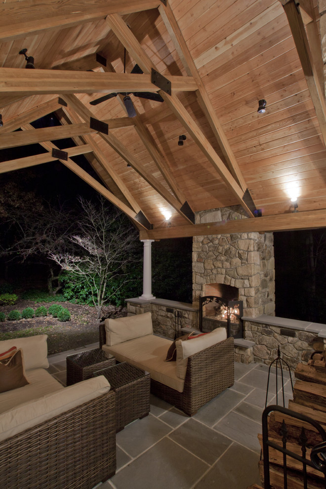 Cette photo montre une grande terrasse latérale chic avec un foyer extérieur, une extension de toiture et des pavés en béton.