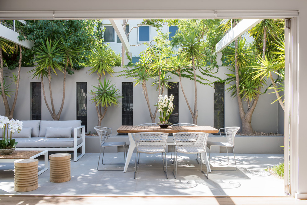 Esempio di un patio o portico minimal di medie dimensioni e dietro casa con lastre di cemento e una pergola
