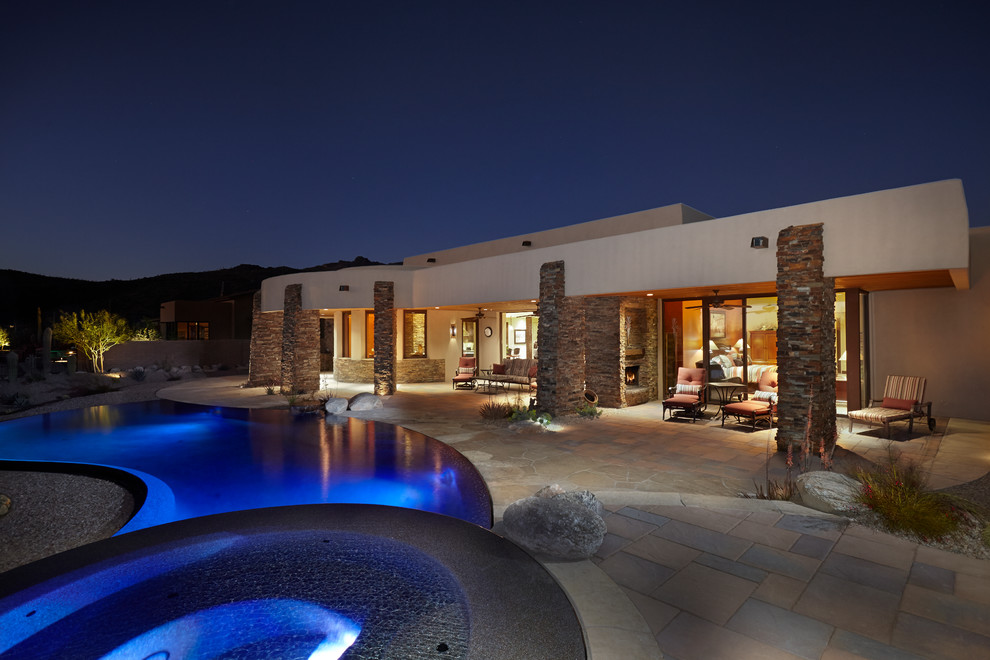 Photo of a large back patio in Phoenix with an outdoor kitchen, natural stone paving and a roof extension.