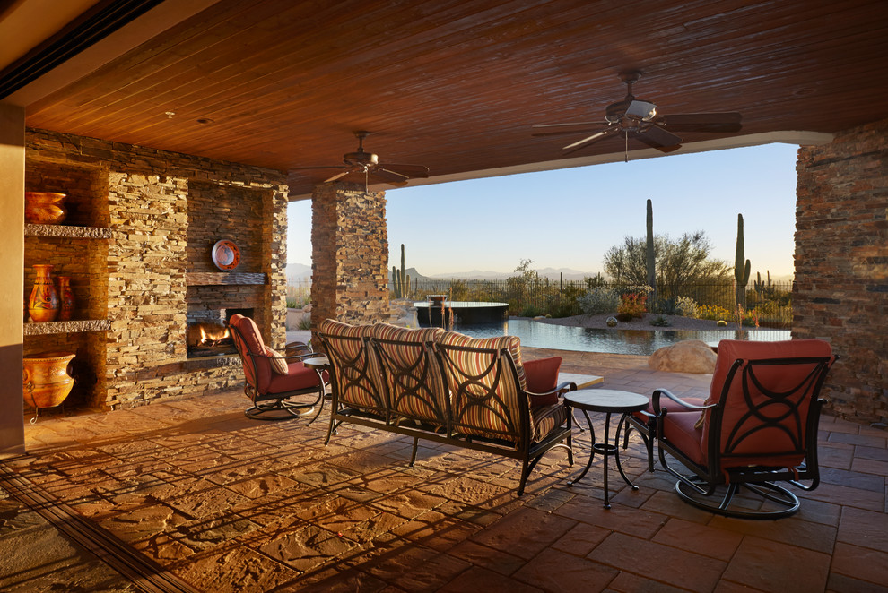 Cette photo montre une grande terrasse arrière sud-ouest américain avec des pavés en béton et une extension de toiture.