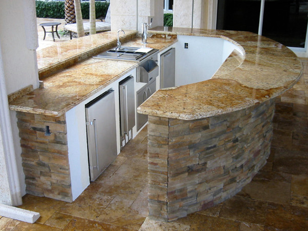 Réalisation d'une grande terrasse arrière design avec une cuisine d'été, du béton estampé et une extension de toiture.