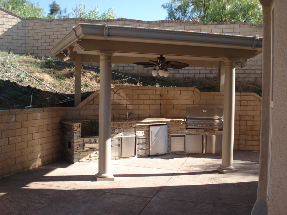 Aménagement d'une grande terrasse arrière contemporaine avec une cuisine d'été, du béton estampé et une extension de toiture.