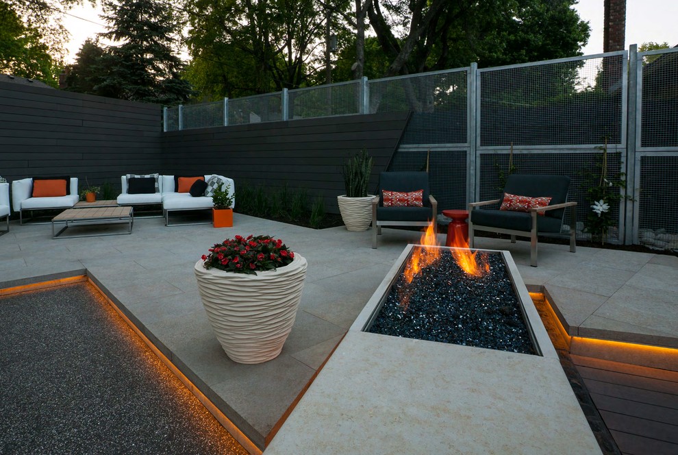 Idée de décoration pour une grande terrasse arrière design avec un foyer extérieur, des pavés en béton et une pergola.