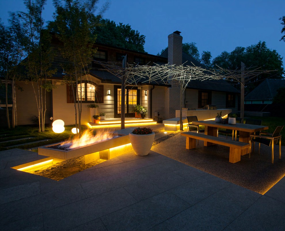 This is an example of a large contemporary back patio in Kansas City with a fire feature, concrete paving and a pergola.