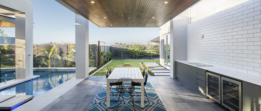 Idee per un patio o portico moderno di medie dimensioni e dietro casa con piastrelle e un tetto a sbalzo