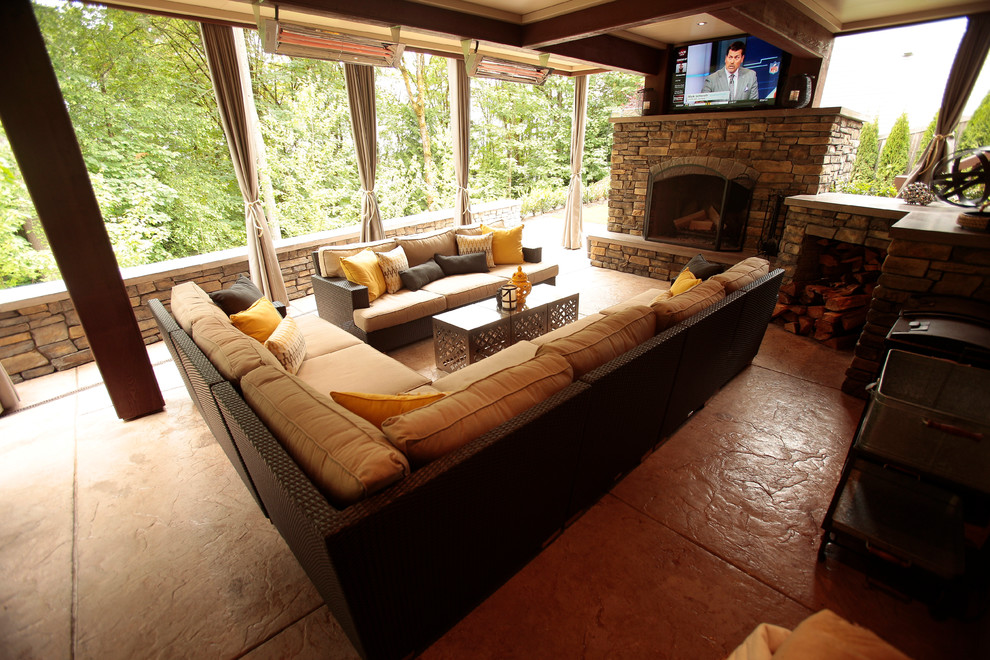 Large modern back patio in Seattle with a fireplace, stamped concrete and a roof extension.