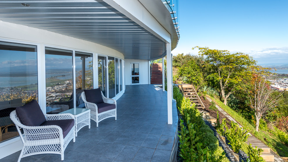 Idée de décoration pour une terrasse arrière minimaliste de taille moyenne avec des pavés en béton et une extension de toiture.