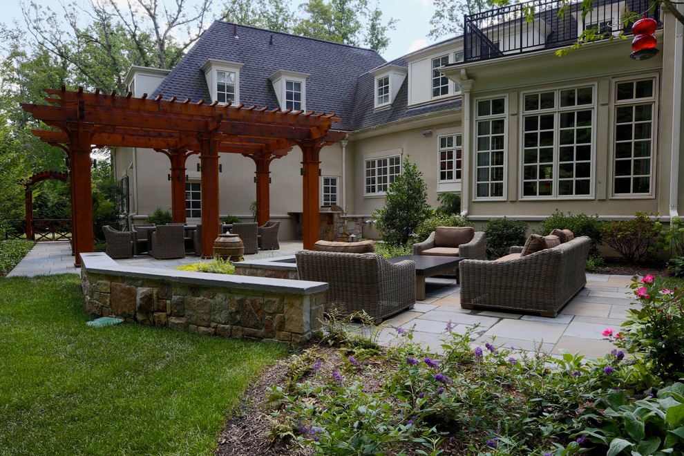 Patio kitchen - large traditional backyard stone patio kitchen idea in New York with a pergola