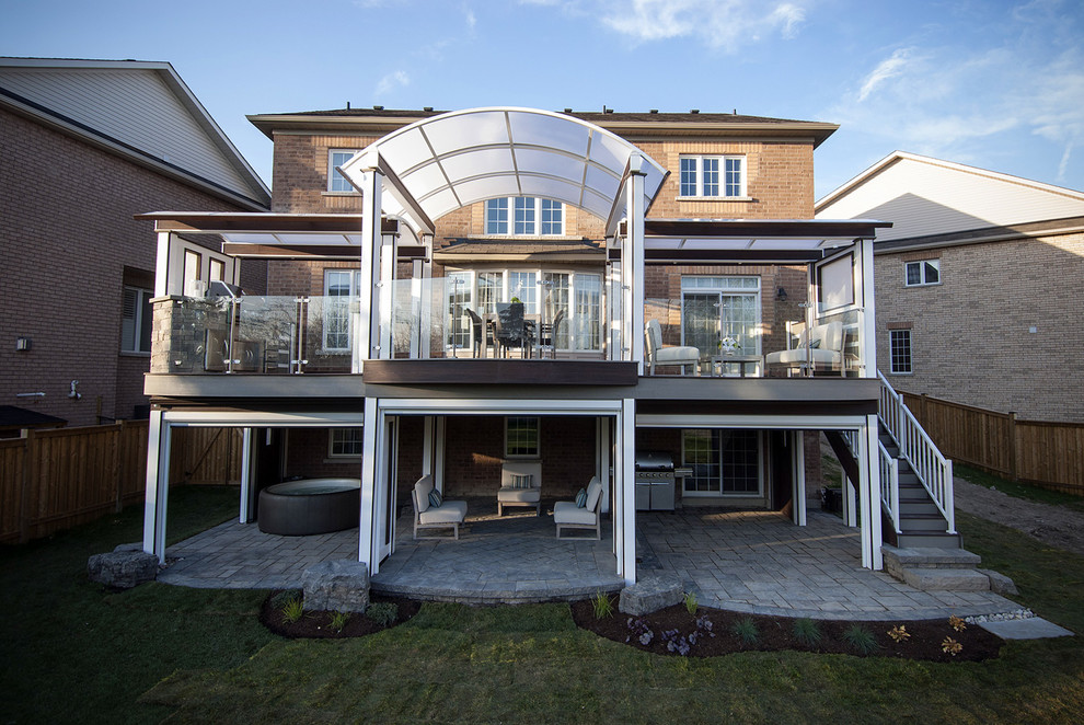 Idées déco pour une grande terrasse arrière moderne avec une cuisine d'été, des pavés en pierre naturelle et une extension de toiture.