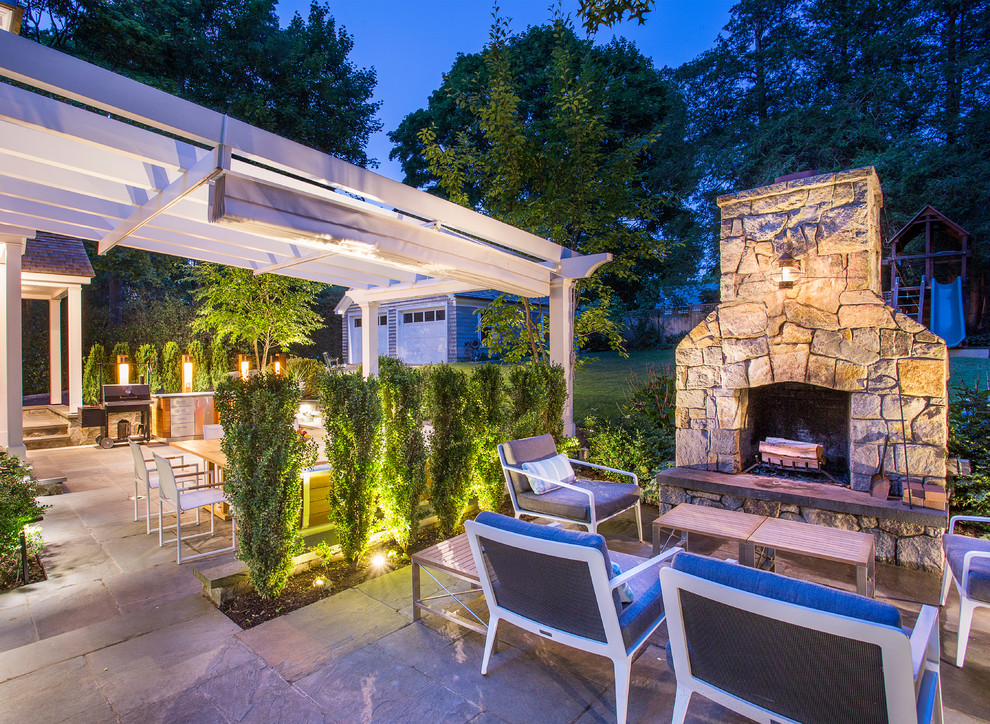 Medium sized contemporary back patio in New York with an outdoor kitchen, natural stone paving and a pergola.