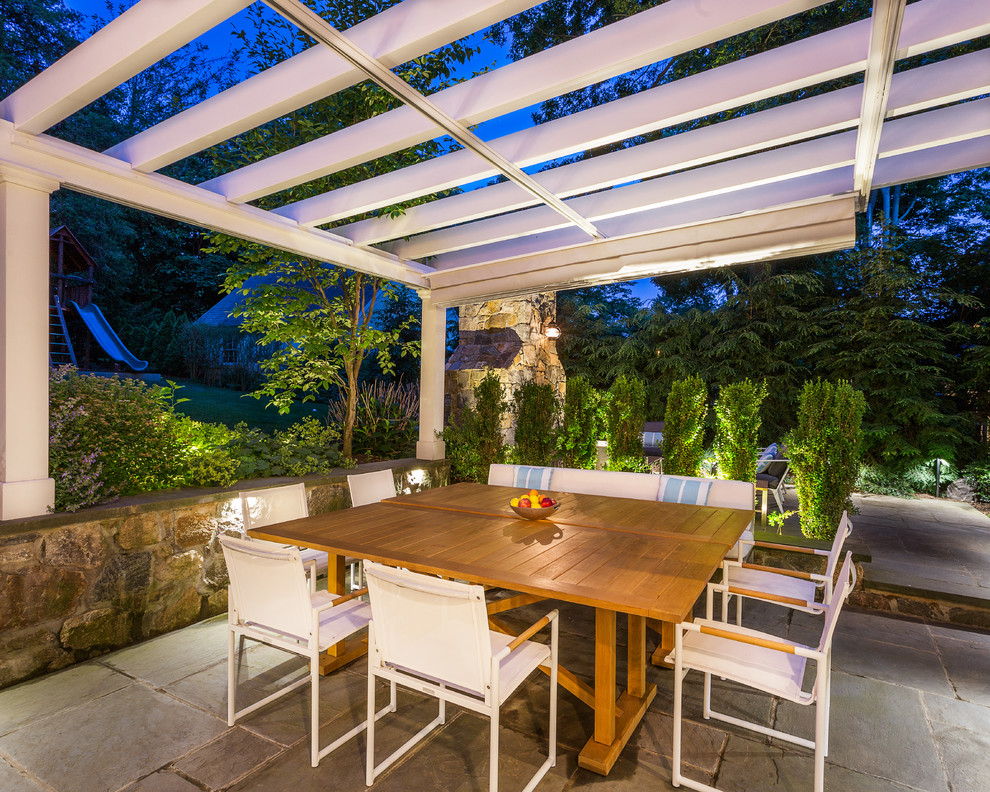 Cette image montre une terrasse arrière design de taille moyenne avec une cuisine d'été, des pavés en pierre naturelle et une pergola.