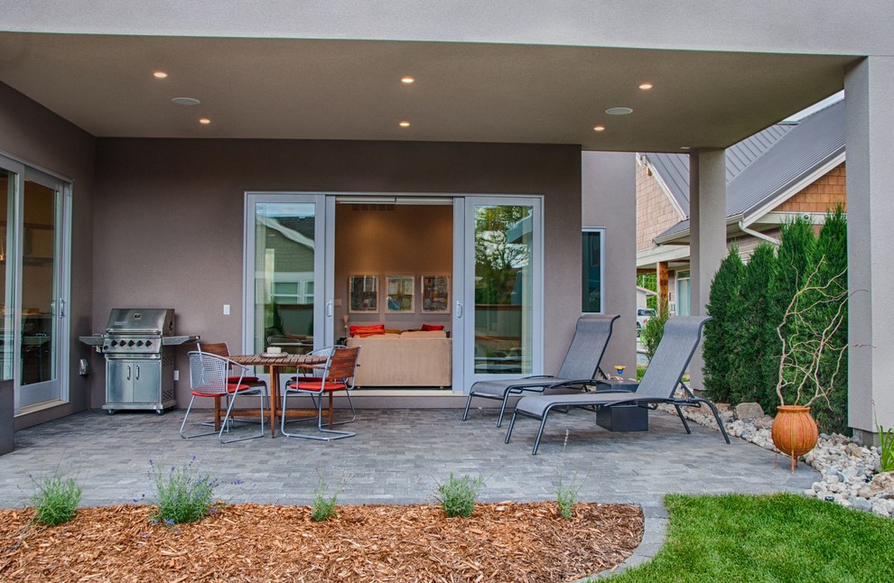 Foto di un patio o portico minimalista di medie dimensioni e dietro casa con pavimentazioni in mattoni e un tetto a sbalzo