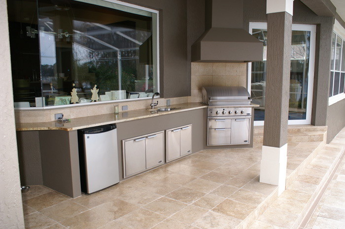 Large minimalist backyard stone patio kitchen photo in Orlando with a roof extension