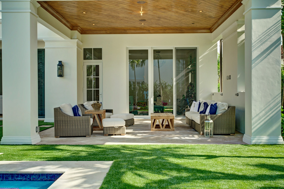 This is an example of a medium sized coastal back patio in Miami with tiled flooring and a roof extension.