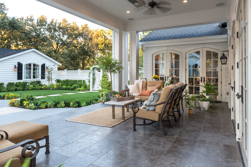 Immagine di un patio o portico chic con piastrelle e un tetto a sbalzo