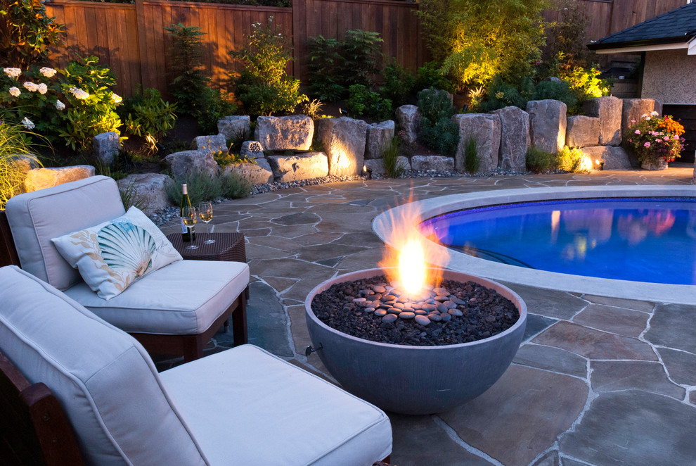 Photo of a large classic back patio in Vancouver with a fire feature, natural stone paving and no cover.