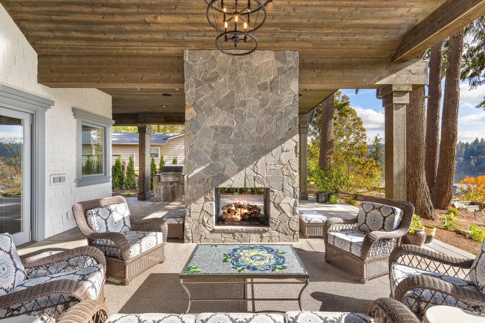 Example of a large backyard concrete paver patio design in Portland with a fireplace and a roof extension