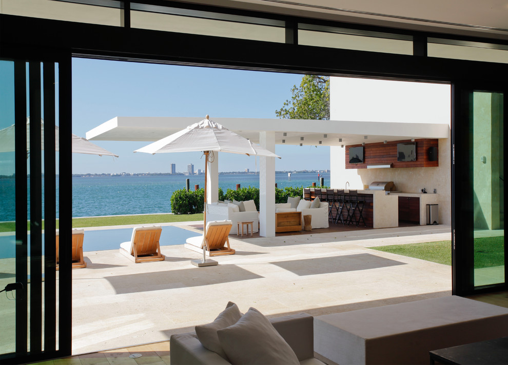 Inspiration for a large modern backyard tile patio remodel in Miami with a roof extension