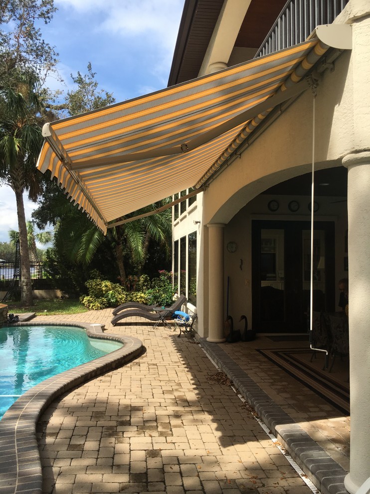 Immagine di un patio o portico mediterraneo di medie dimensioni e dietro casa con pavimentazioni in mattoni e un parasole