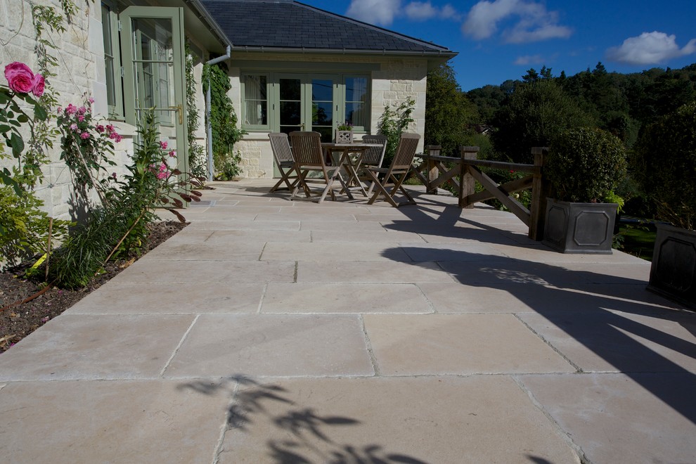 Idee per un patio o portico country con pavimentazioni in pietra naturale