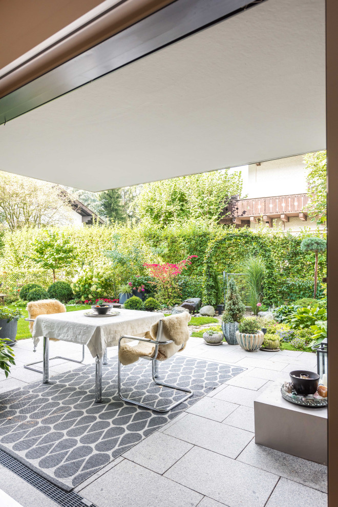 Cette image montre une terrasse avec des plantes en pots latérale design avec une extension de toiture et des pavés en pierre naturelle.