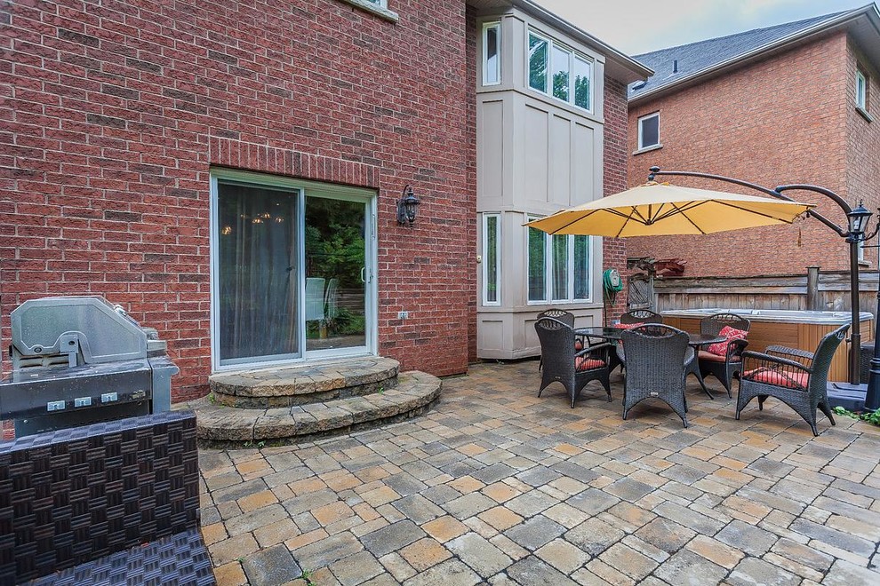 Photo of a large traditional back patio in Toronto with a potted garden, concrete paving and an awning.