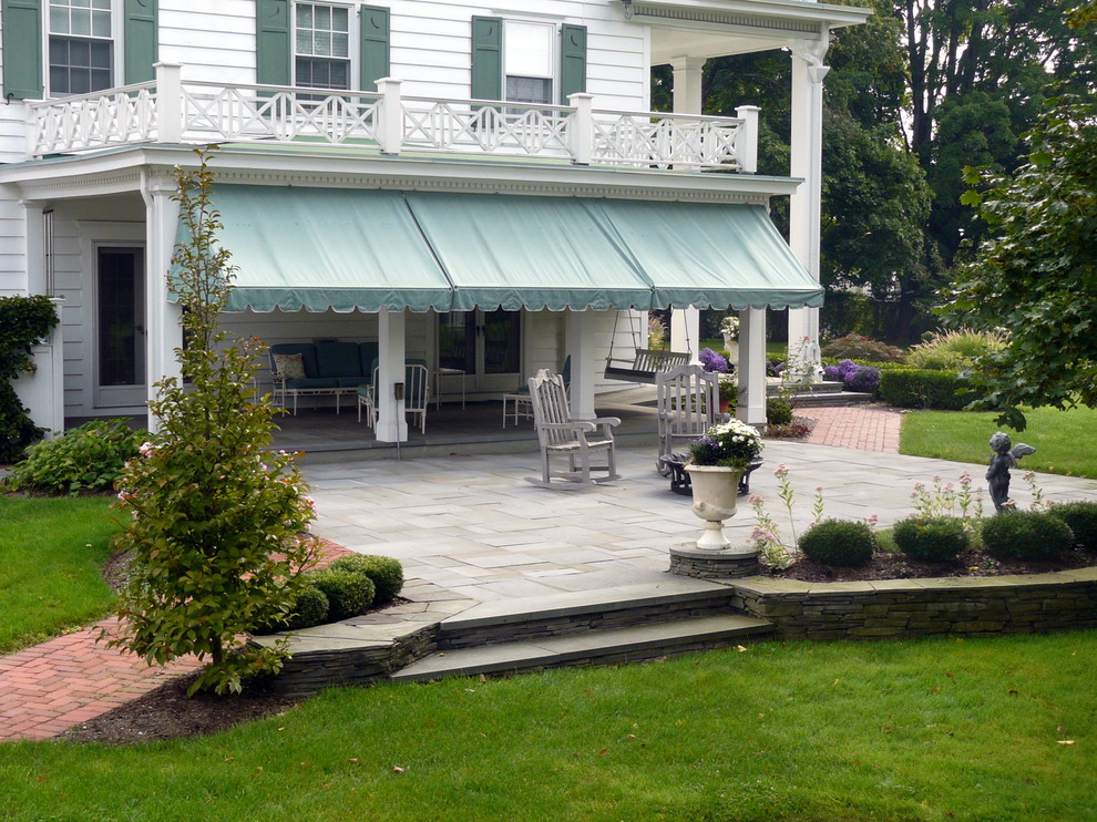 Diseño de patio tradicional grande en patio lateral con adoquines de piedra natural y toldo