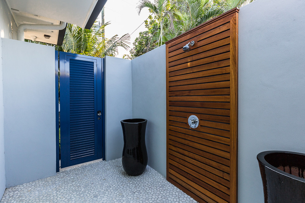 Inspiration for a medium sized contemporary side patio in Miami with an outdoor shower, natural stone paving and a roof extension.
