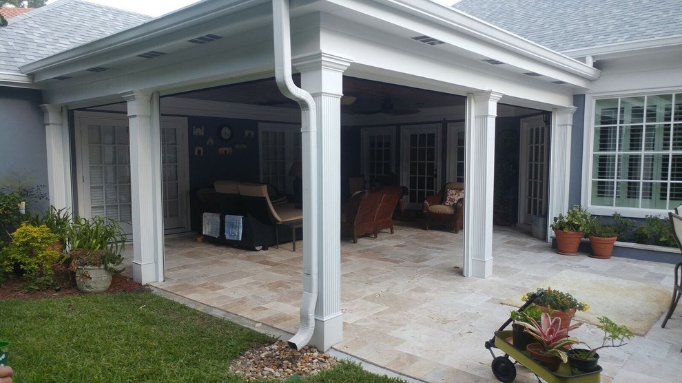 Immagine di un patio o portico tropicale di medie dimensioni e dietro casa con piastrelle e un tetto a sbalzo