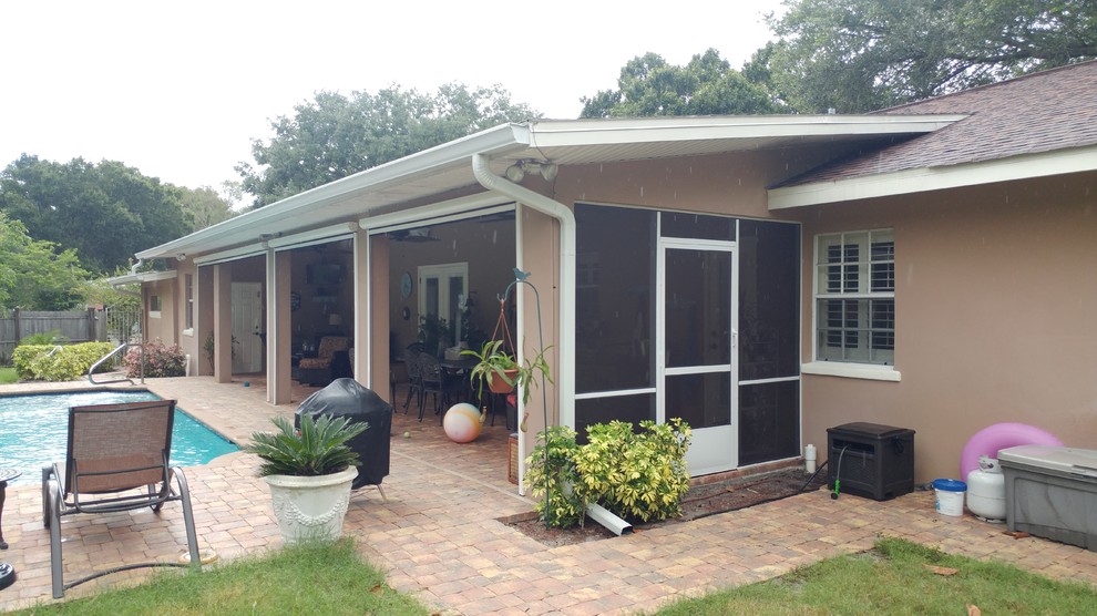 Immagine di un patio o portico minimal di medie dimensioni e dietro casa con pavimentazioni in mattoni e un tetto a sbalzo