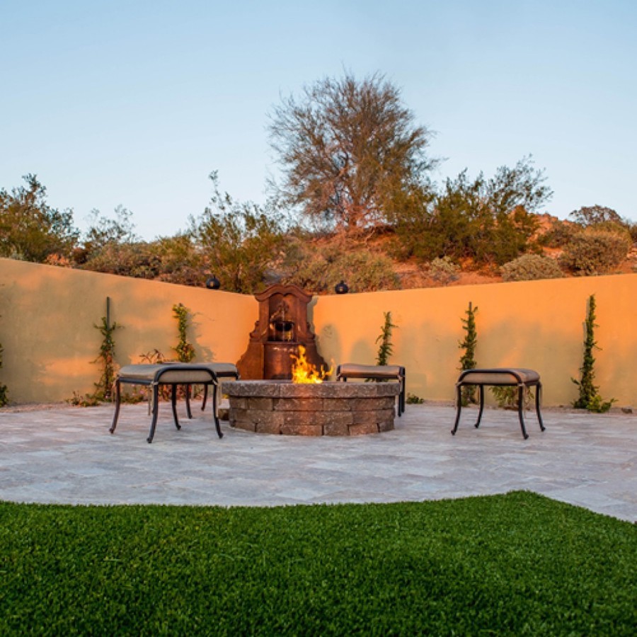 Mediterranean back patio in Phoenix with a fire feature, natural stone paving and no cover.