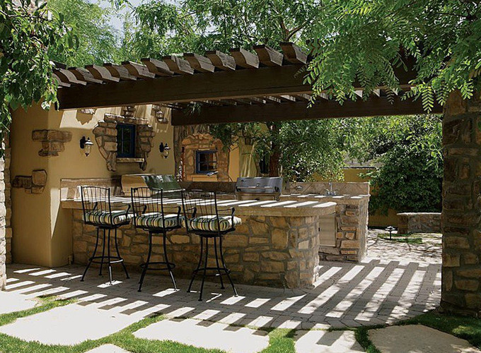 Diseño de patio mediterráneo en patio trasero con cocina exterior, adoquines de ladrillo y pérgola