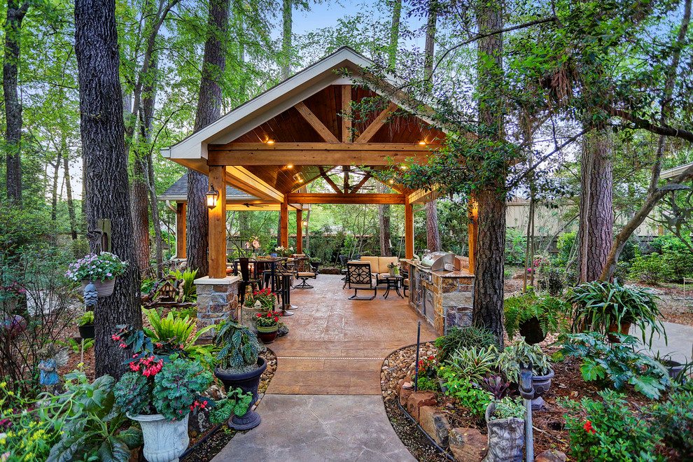 This is an example of a medium sized rustic back patio in Houston with an outdoor kitchen, stamped concrete and a gazebo.