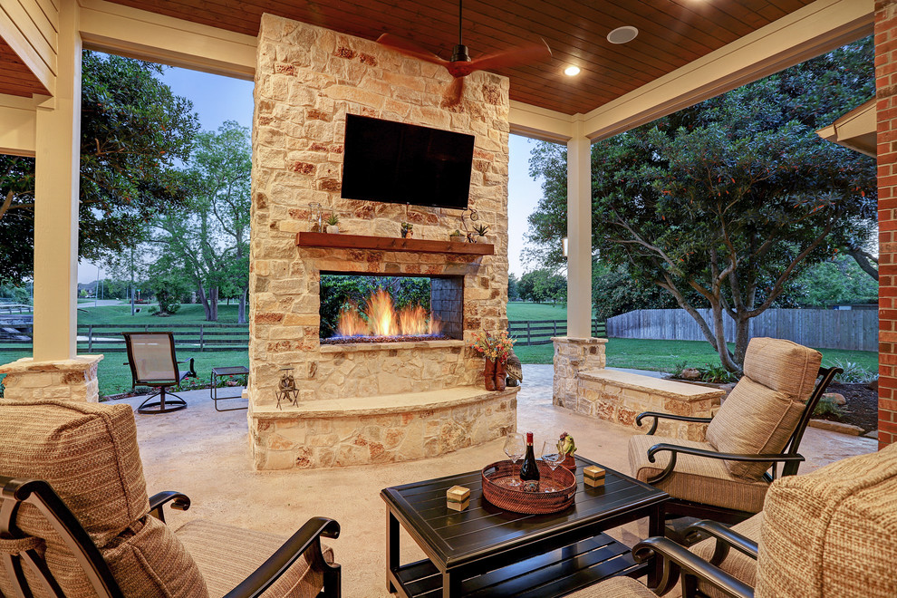 Example of a mid-sized classic backyard stamped concrete patio design in Houston with a fireplace and a roof extension