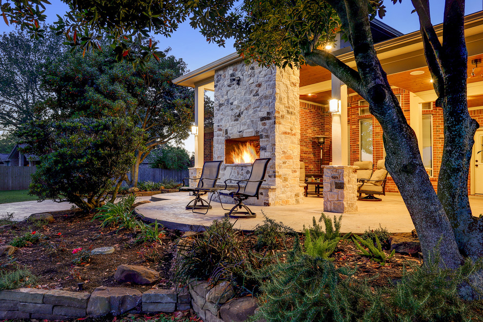 Inspiration for a medium sized traditional back patio in Houston with a fireplace, stamped concrete and a roof extension.