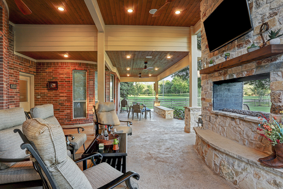 Patio - mid-sized traditional backyard stamped concrete patio idea in Houston with a fireplace and a roof extension