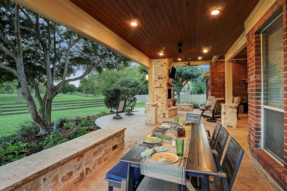 Inspiration for a mid-sized timeless backyard stamped concrete patio remodel in Houston with a fireplace and a roof extension