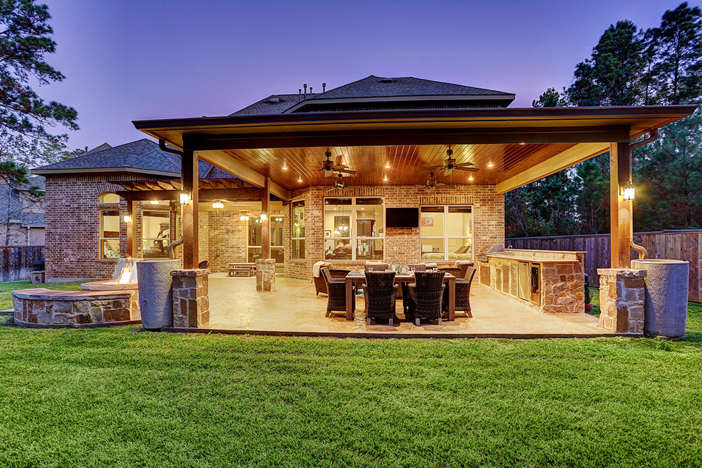 Foto di un patio o portico classico di medie dimensioni e dietro casa con un focolare, cemento stampato e un tetto a sbalzo