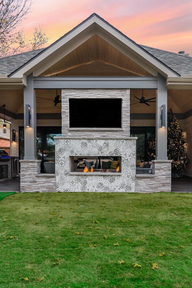 Immagine di un patio o portico minimalista di medie dimensioni e dietro casa con un focolare, piastrelle e un tetto a sbalzo